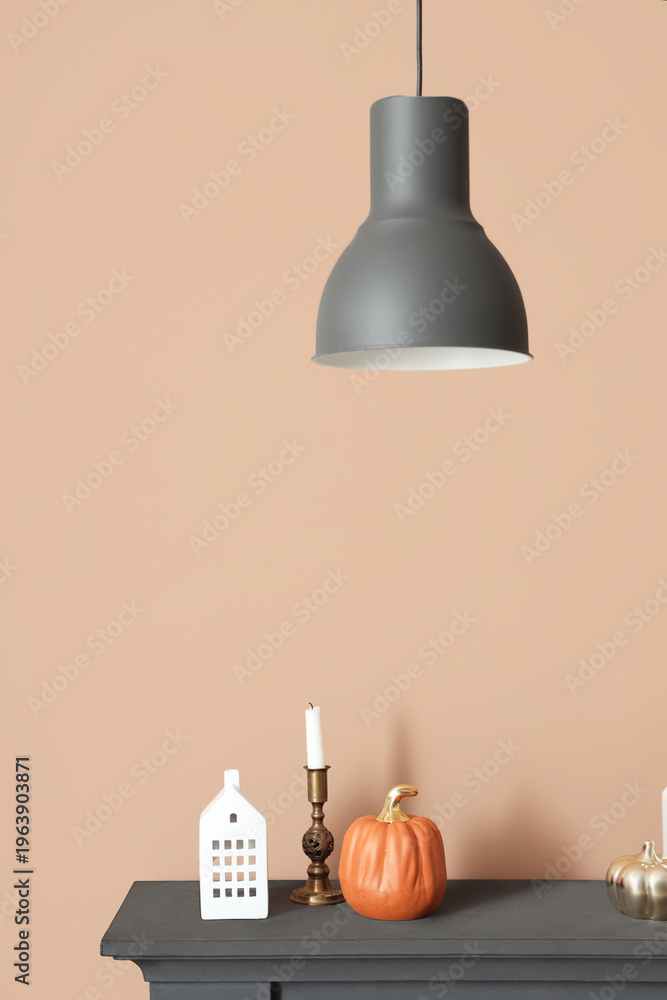 Fototapeta premium Pumpkins, candle and decorative house on mantelpiece near brown wall