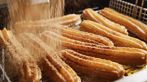 Churros frying in bubbling hot oil in a professional deep fryer