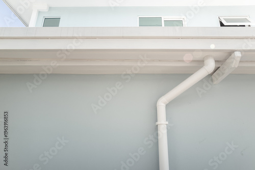 Architectural view of modern contemporary building featuring rain gutter system with white PVC gutter and downspout, supported by steel frame structure, reflecting construction quality and design.