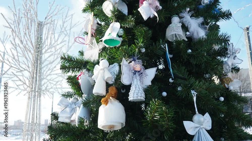 Colorful ornaments and white ribbons adorn a stunning Christmas tree set against a backdrop of crisp winter skies. Soft snowflakes fall gently, creating a holiday atmosphere