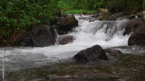 Clear river flow with refreshing scenery, showing crystal water, natural stones, and calming atmosphere in a serene tropical landscape