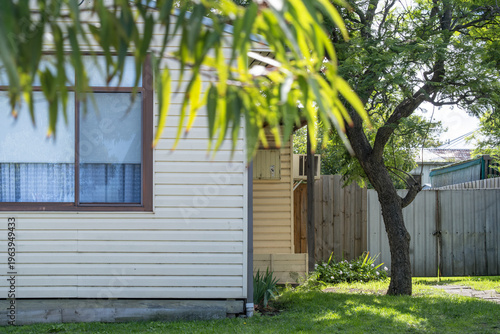 Foto A modest weatherboard cottage or house exterior showcases horizontal cladding and humble metal gate
