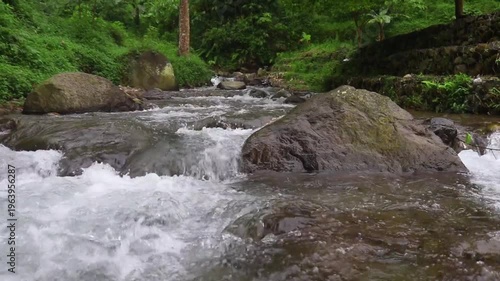 Clear river flow with refreshing scenery, showing crystal water, natural stones, and calming atmosphere in a serene tropical landscape
