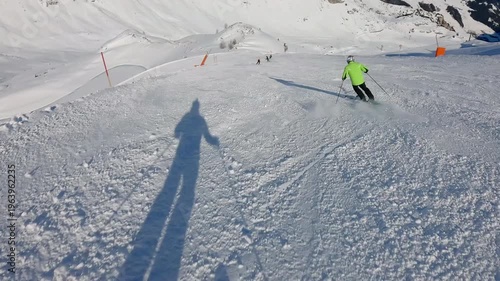 Skier carve turns on a pristine snowy piste during a clear winter day. Low angle slow motion view