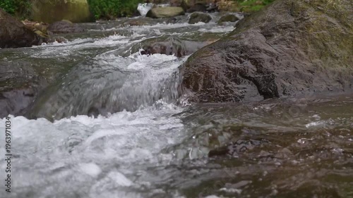 Clear river flow with refreshing scenery, showing crystal water, natural stones, and calming atmosphere in a serene tropical landscape