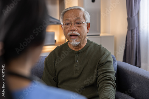 Senior man counseling caregiver home living room support conversation therapy healthcare trust Senior man talks with caregiver sofa cozy living room, sharing concern and finding calm support