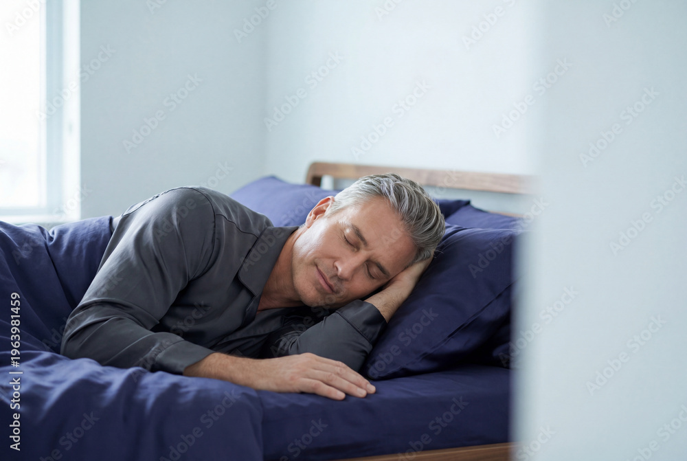 Fototapeta premium Peaceful middle aged man with glowing skin sleeping soundly in a bed