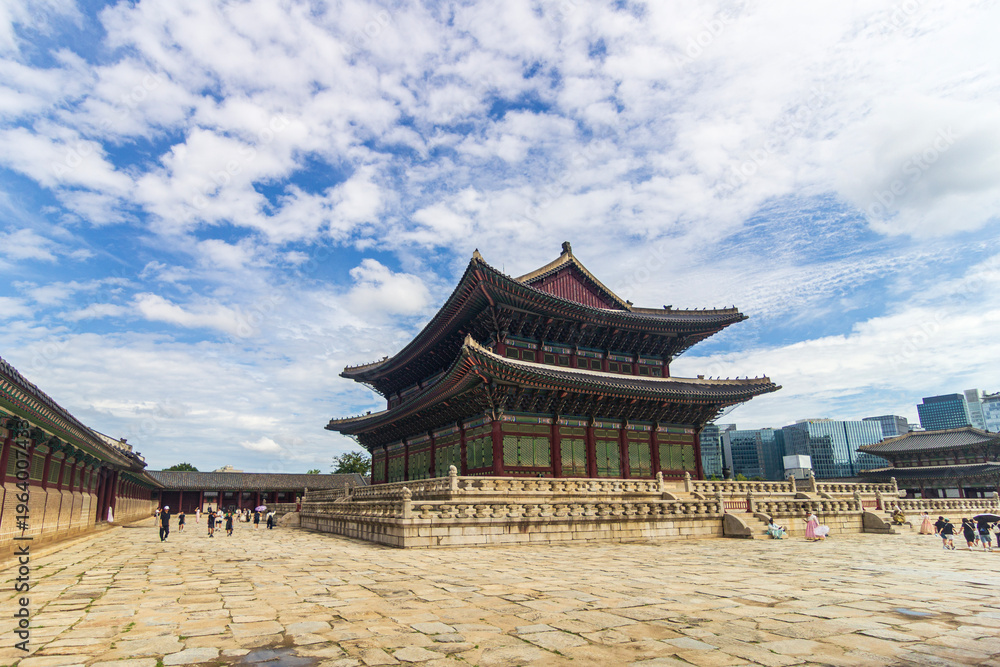 Fototapeta premium Majestic Korean palace architecture with symmetrical stone courtyard and layered tiled roof under dramatic sky, traditional Asian heritage landmark, cultural travel destination concept