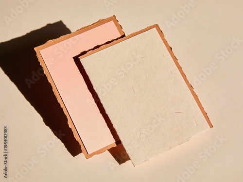 Two blank textured invitation cards with deckled edges and soft peach beige surface colors on a warm sand background for premium wedding or event stationery mockup