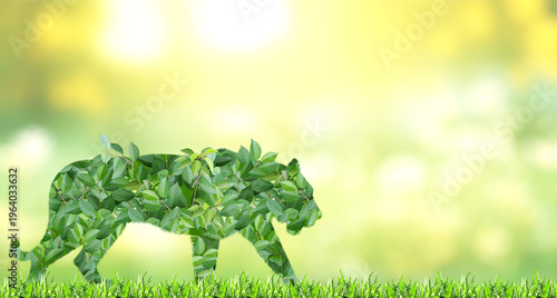 Tiger silhouette made of green leaves on sunny background. Ecology, global ecological resource, go green concept. Environmental conservation, wildlife protection, Eco-friendly, Green Energy