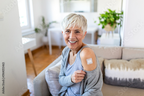 Foto Smiling senior woman showing adhesive bandage on shoulder after vaccination