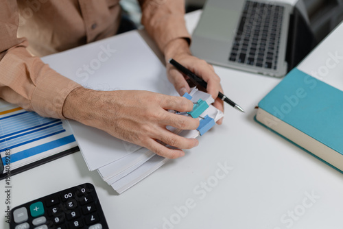 Bild auf Leinwand Close up of person organizing financial documents with clips on desk, representing paperwork management, accounting process, office organization, and financial record keeping