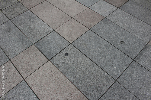 Texture of gray and beige square paving tile. Pattern of sidewalk tiles in the street. Concrete pavers close up background.	