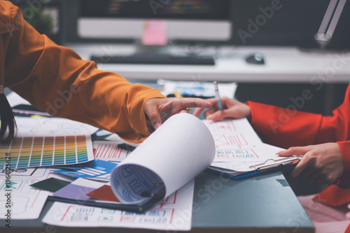 Team of uxui designers pointing at computer screen, discussing new mobile app design in the office