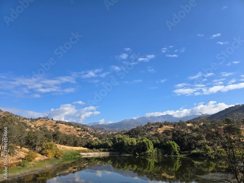 Mountain lake reflection under blue sky and scattered clouds