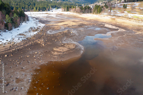 Drone aerial view of dried lake bed with exposed shoreline, sand formations and natural patterns. Environmental concept of drought and low water levels