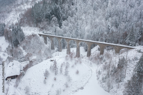 Aerial drone view of historic Ravenna railway viaduct surrounded by snowy forest in Black Forest, Germany. Scenic winter landscape and architecture