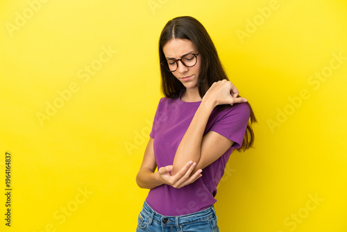 Young French woman isolated on yellow background with pain in elbow