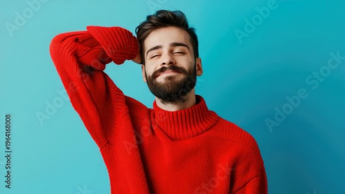 Man smiling at camera, casual style, red sweater over top, blue wall background.