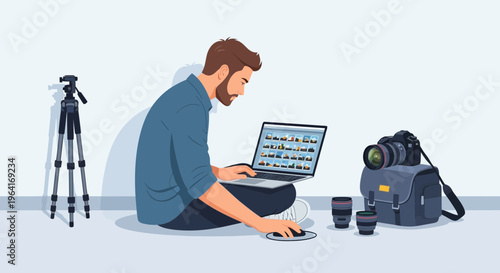 Man working on laptop with photography equipment around him.
