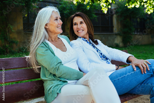 Slika na platnu Beautiful senior women meeting outdoors in the city and sitting on the bench at