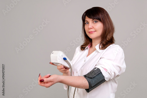 A female medic measures blood pressure with an automatic tonometer.