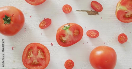 Displaying halved tomato with green calyx amid whole tomatoes on white board, red symbols drifting