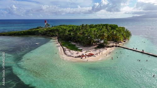 Aerial drone footage of Ilet du Gosier island near Pointe-à-Pitre, Guadeloupe. Scenic tropical landscape with white sandy beach, turquoise Caribbean Sea and iconic lighthouse. Popular travel destinati