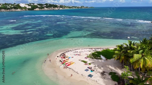Aerial drone footage of Ilet du Gosier island near Pointe-à-Pitre, Guadeloupe. Scenic tropical landscape with white sandy beach, turquoise Caribbean Sea and iconic lighthouse. Popular travel destinati
