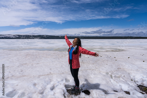 Woman hiker with arms outstretched on frozen Yellowstone Lake, Wyoming. 