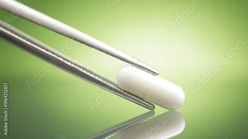 Precise Handling of a White Capsule by Tweezers on a Reflective Green Surface, Illustrating Pharmaceutical Research and Development