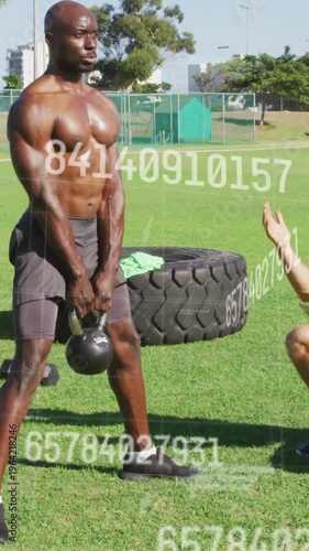 Vertical video: Coach cueing, athlete lifting kettlebell on field for strength, metrics overlaying