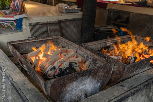 Foto Glowing charcoal briquettes and bright orange flames burn in two metal braziers,