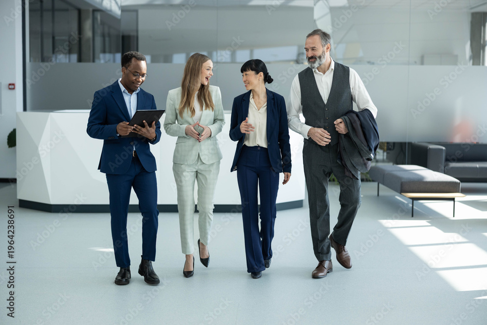 Fototapeta premium Diverse business professionals walking through a modern office building, discussing strategy and collaborating on a new project