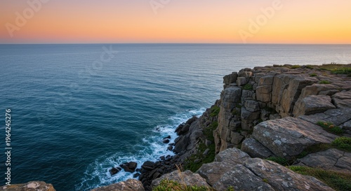 Elevated rugged coastline meets tranquil ocean waters under a pastel colored sky