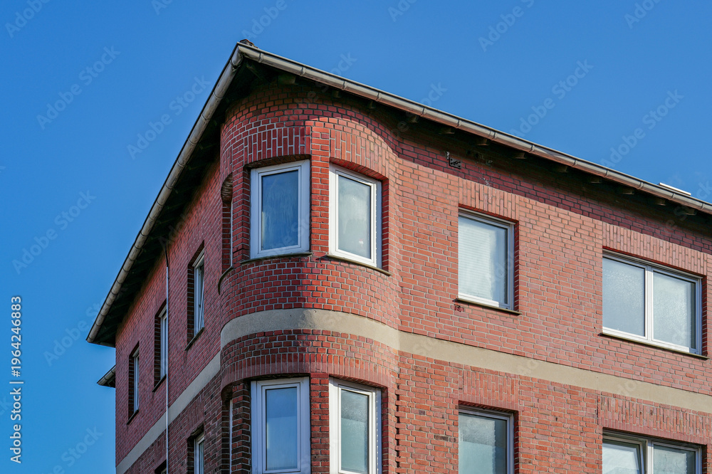 Obraz premium Red brick building facade with bay windows against blue sky