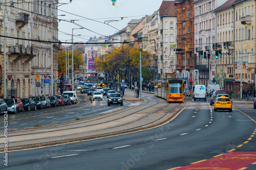 Urban city scene in Budapest with yellow trams and car traffic on the road
