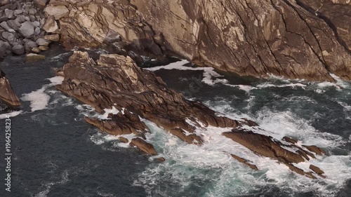Rugged coastal cliffs meet the turbulent ocean waves.