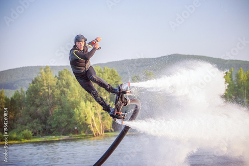 Tableau sur toile A flyboarder performs an impressive stunt above the shimmering water, propelled by powerful jets