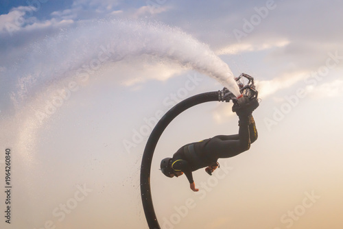 Принти на полотні Athlete deftly maneuvers on a flyboard, soaring high above the water with a powerful jet of water propelling them up
