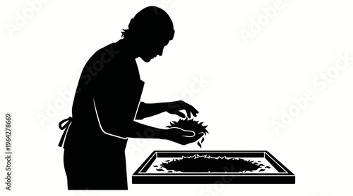 Person tending to plants or seeds on a tray with hands in silhouette