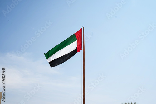 UAE national flag waving against a blue sky. Concept of patriotism, identity, and Middle Eastern country.