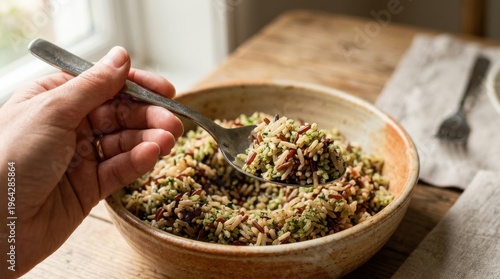 Hand holding fork with healthy quinoa salad in rustic kitchen setting