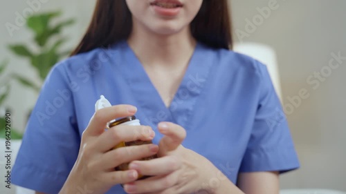 Caregiver elderly care home nurse healthcare medicine dropper glass uniform pours liquid for patient support, daily routine with pill bottle opened for safe dose management and comfort to older adult