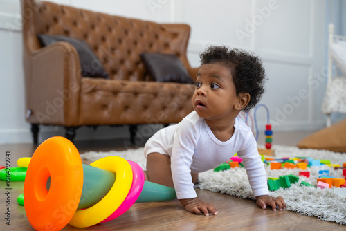 A baby is crawling on the floor and playing with a toy