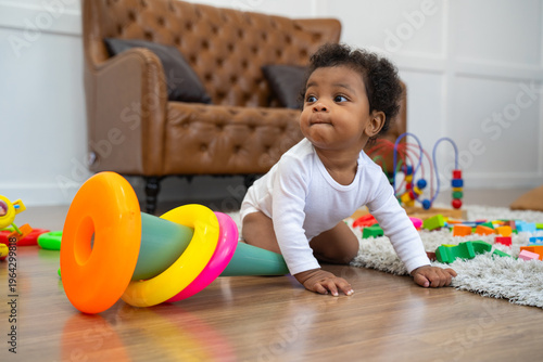 A baby is crawling on the floor and playing with a toy