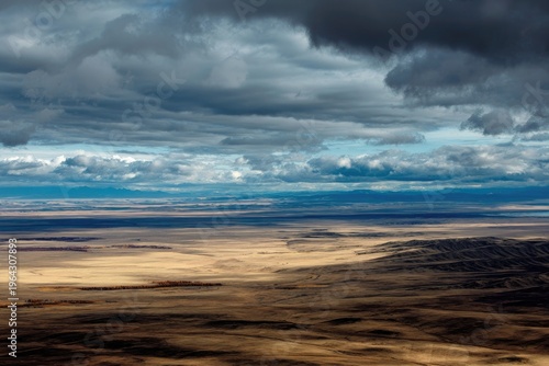 Expansive Plains Under Dramatic Stormy Sky Aerial View Golden Hour Light Rugged Terrain Wide Landscape
