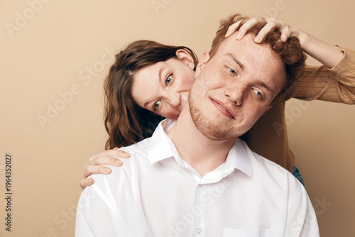 Photography Young couple in casual clothes playfully interact with each other, woman smiling behind man with hand on his head