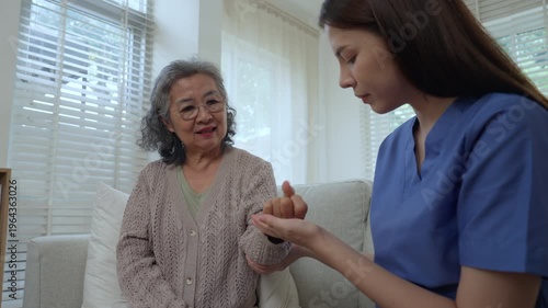 Caregiver elderly care home nurse support woman trust and comfort, gentle moment as nurse holds older adult hand on sofa in bright living room, compassionate health guide for safe, heard visit at home
