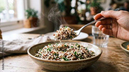 Hand serving steaming rice salad with herbs in cozy kitchen
